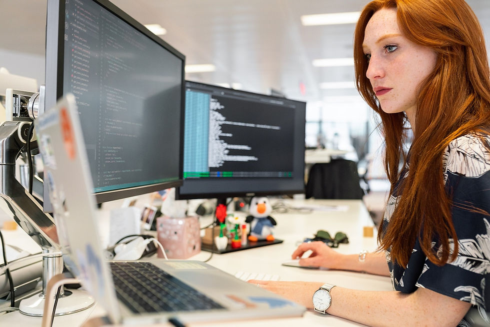 Woman working at laptop with multiple screens