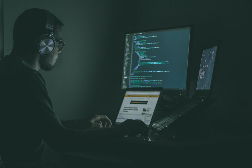 Man wearing headphones and looking at program code on his screen